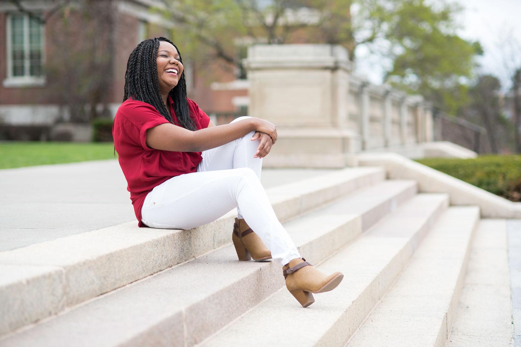 University of Rochester graduate students sitting outside on the steps to campus, laughing