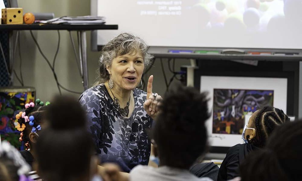 Sydney Greaves teaching arts integration lesson sitting on floor with children.