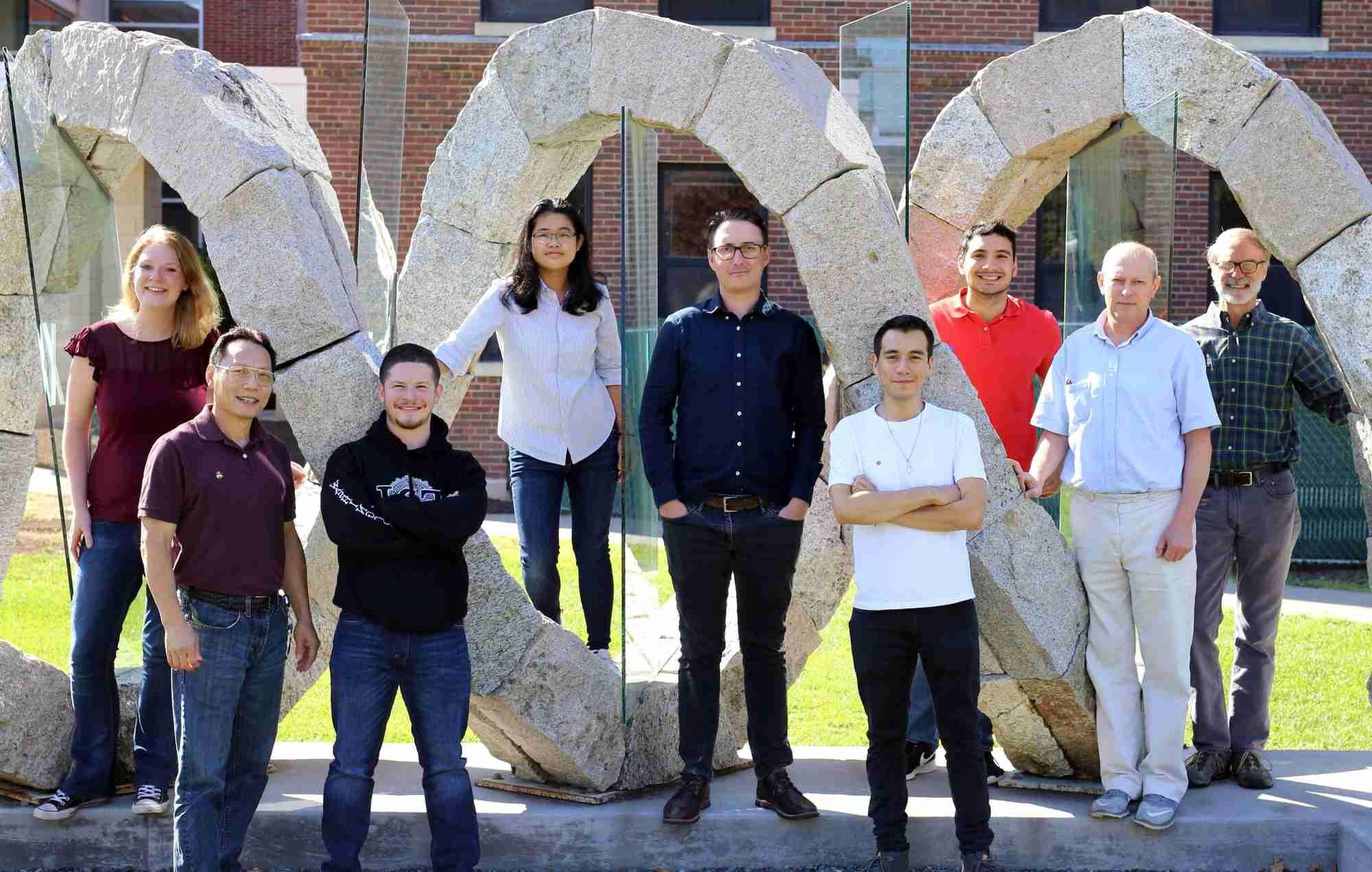 Mitch O'Connell poses with the members of his lab need a helix-shaped sculpture. 